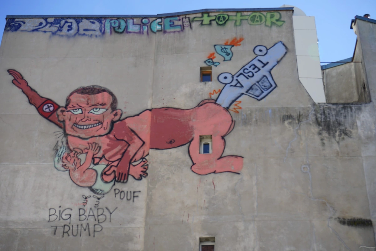 graffiti image of elon musk performing a nazi salute with trump dressed as a baby suckling his tit